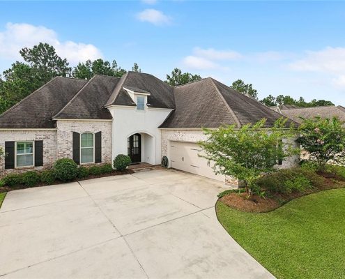 The steeply pitched rooflines and black window shutters add a sophisticated touch, while the wide driveway leads to a spacious two-car garage.