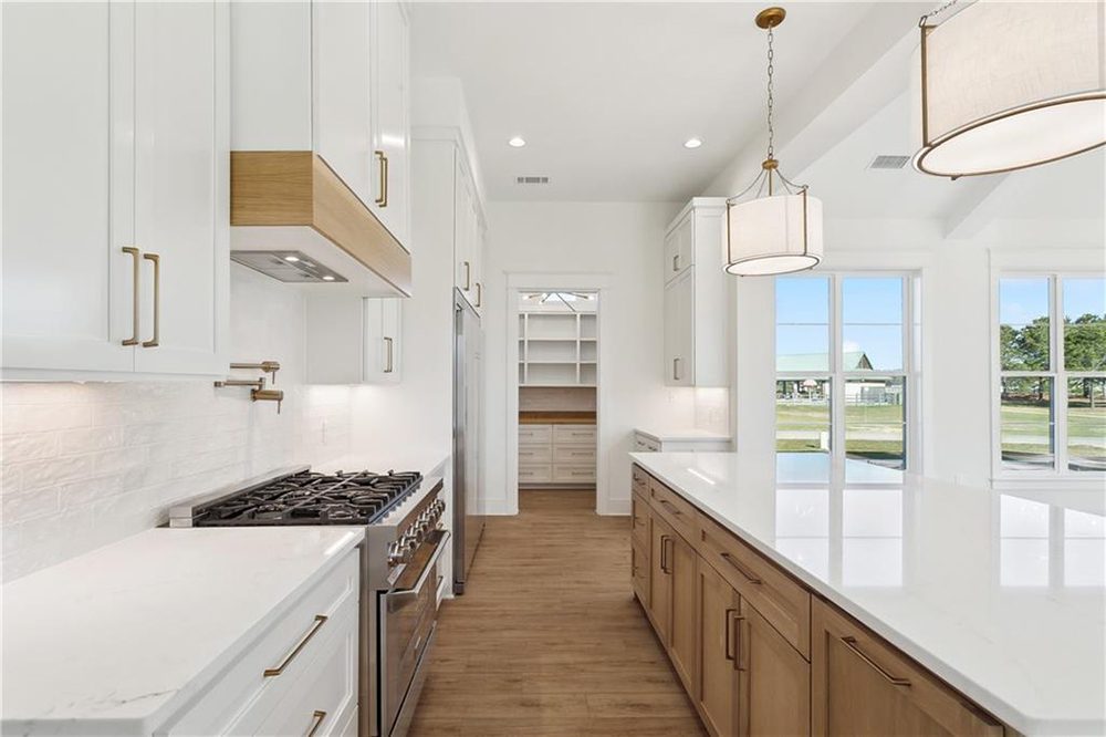 12-Kitchen Lighting 1174 Audubon Pkwy The expansive quartz island provides generous prep and seating space, while large windows flood the room with natural light and offer beautiful views of the outdoors.