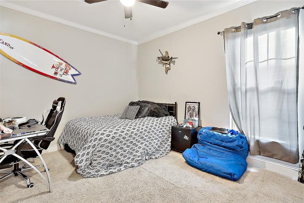 13--3033 Lost LakeTeen Bedroom Soft gray curtains filter natural light, enhancing the neutral color palette and cozy carpet flooring. With a mix of practicality and personality, this space is perfect for both work and play.