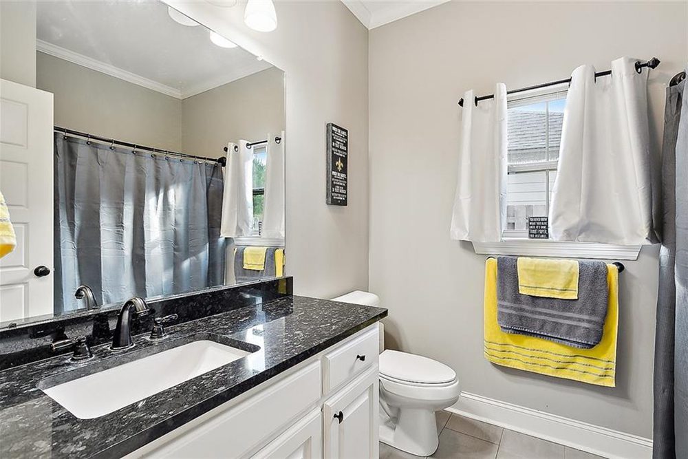 14-3033 Lost Lake Bathroom A window with white curtains allows natural light to filter in, making the space feel airy and inviting. With a classic combination of contemporary and cozy elements, this bathroom is both beautiful and practical.
