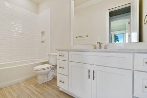 Guest bathroom with a shower tub combo. The bathroom has a large vanity and nice custom tile floors.