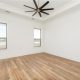 A master bedroom that is sleek and clean in design with a custom wide ceiling fan.