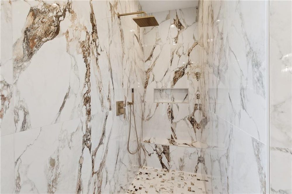 19-Gorgeous Walk In SHower 1174 Audubon Pkwy The shower floor contrasts beautifully with mosaic tiling that echoes the wall tones while adding subtle texture underfoot. Bright, recessed lighting ensures every marble detail gleams, creating a serene yet statement-making space perfect for daily indulgence.