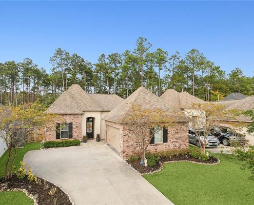 This stunning French Country-style home boasts a beautifully crafted brick exterior with warm, earthy tones that create a timeless and inviting look. The architectural design features elegant hip roofs and a charming arched entryway, which is complemented by soft beige stucco accents. Classic black shutters enhance the traditional aesthetic, while the neutral-toned garage door blends seamlessly with the brickwork. The well-manicured landscaping includes lush greenery, neatly edged flower beds, and a curved driveway that enhances the home’s curb appeal. Set against a serene wooded backdrop, this home offers a perfect blend of rustic charm and modern elegance, making it an ideal choice for those who appreciate classic yet refined architecture.