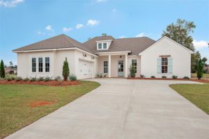 This home features a side entry garage and a covered front porch. The house exterior features white brick and wood siding.