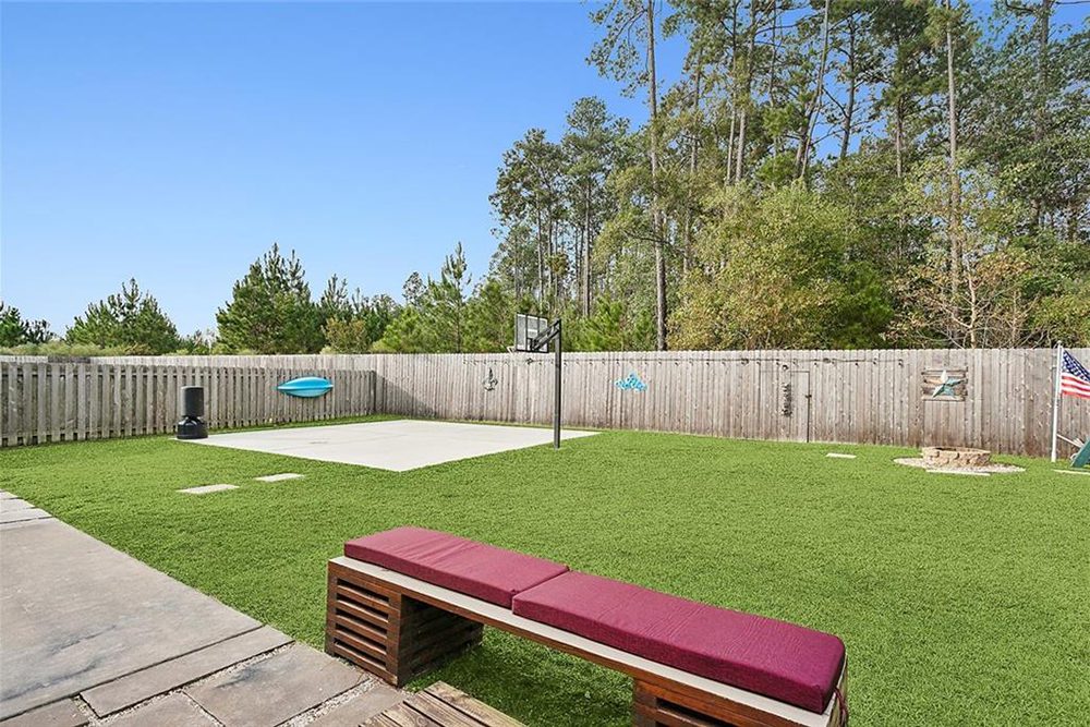 20--3033 Lost Lake Fenced In Yard A custom-built bench with red cushions offers a comfortable spot to unwind, while the surrounding trees and tall wooden fence provide a private retreat.