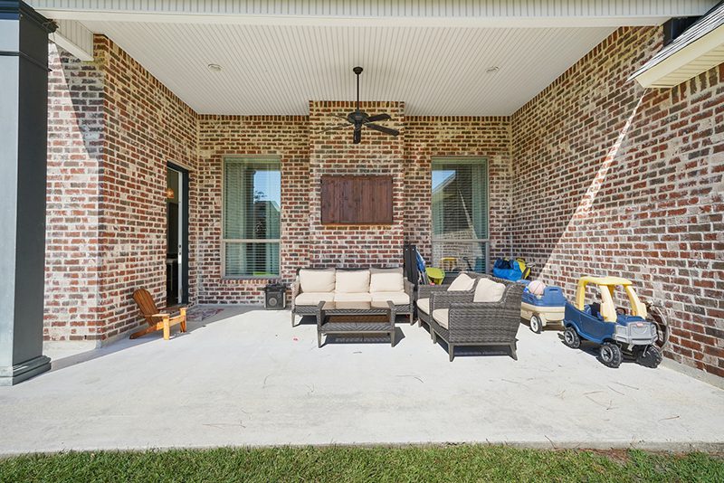 Covered patio that looks out onto the spacious fenced-in backyard. This patio is complete with a ceiling fan and custom lighting.