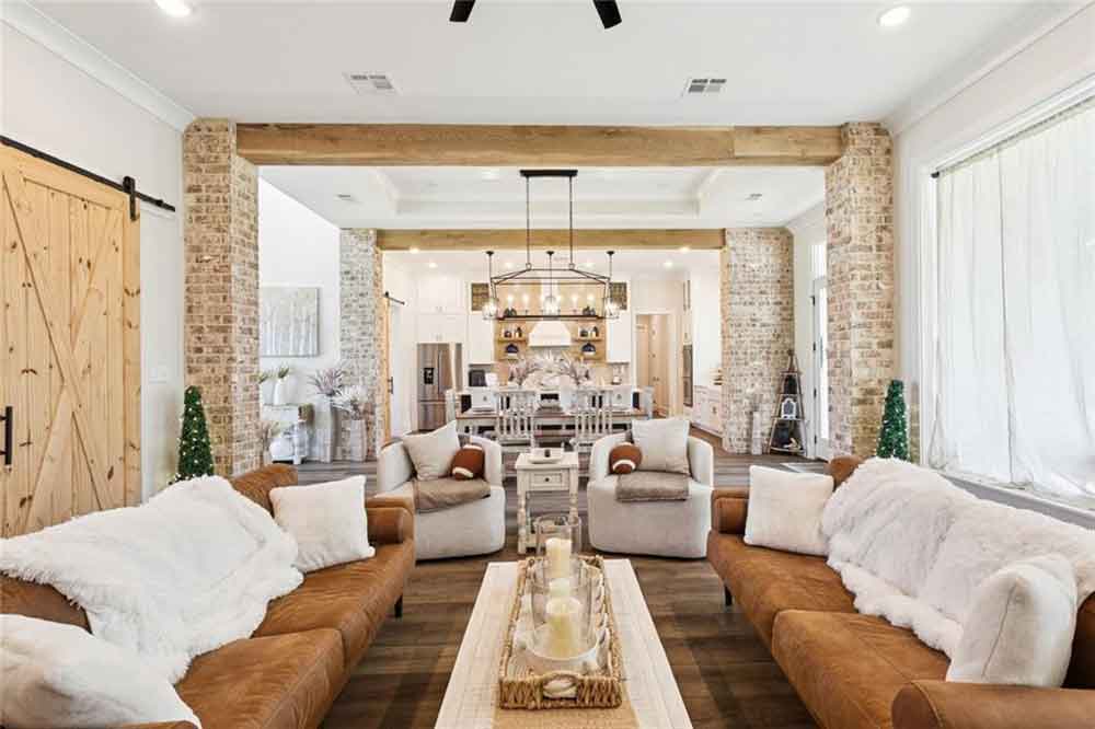Rustic brick columns and exposed wood beams add architectural charm, while cozy seating and warm textures create an inviting atmosphere perfect for entertaining or relaxing with family.