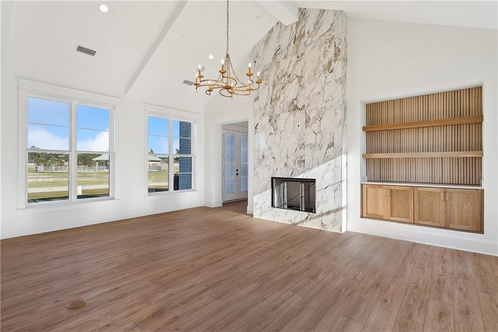 6-Built In Shelving 1174 Audubon Pkwy Natural light floods the room through multiple oversized windows, while the custom wood built-in shelving with slatted detailing adds warmth and functionality to the sophisticated space.