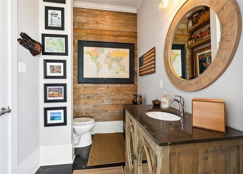 The vanity is fashioned from weathered wood, featuring a built-in sink, and is adorned with an American flag and a framed map, infusing the room with a traveler's spirit.